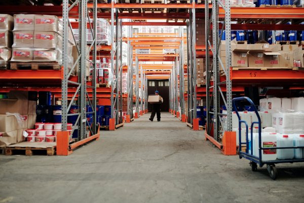 inside a factory with shelving around a person walking down a hallway